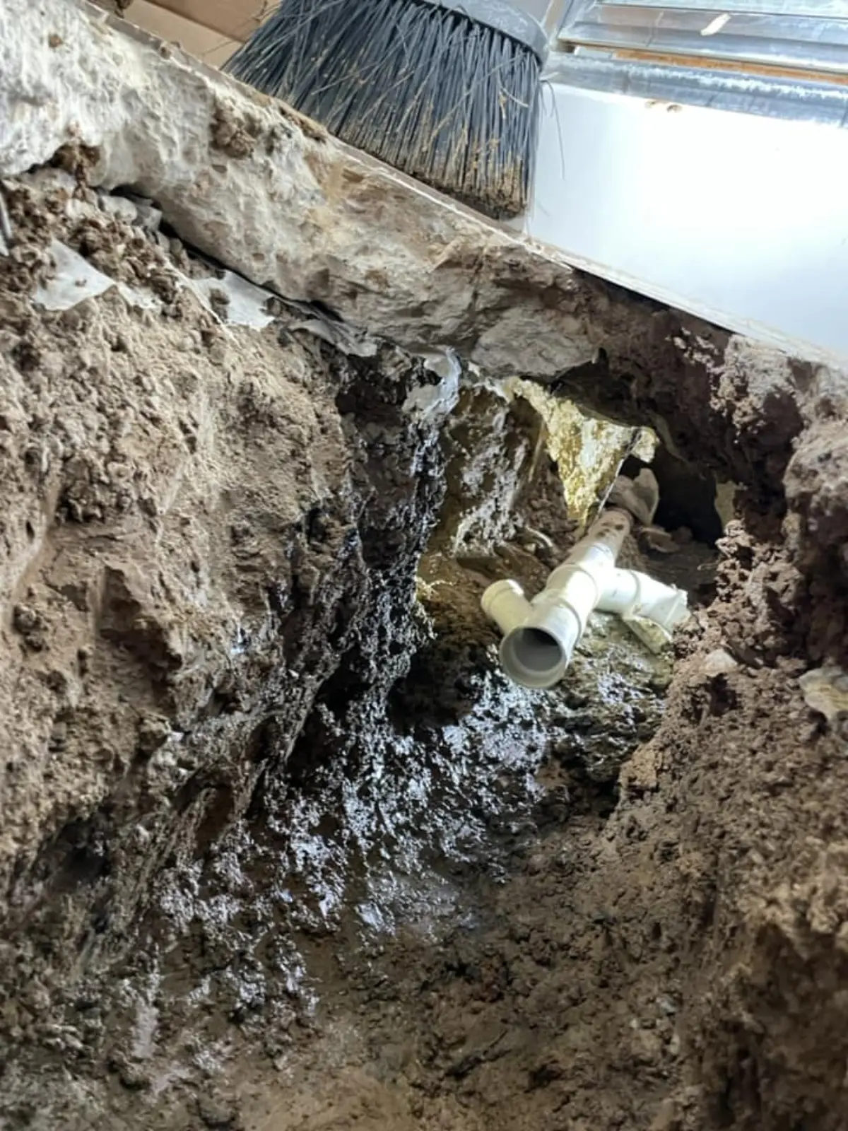 Underground excavation around a broken sewer line under a home.