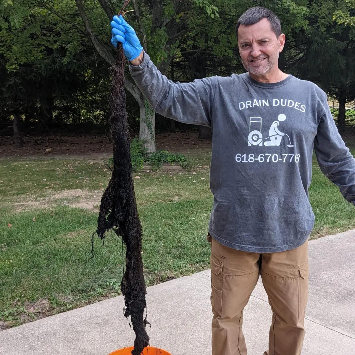 Drain Dudes founder holding evidence of a recently cleared sewer line.